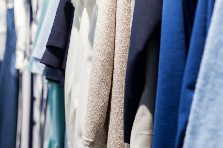 Collection of wear made of natural fabrics and hanging in shop with shiny light on blurred background